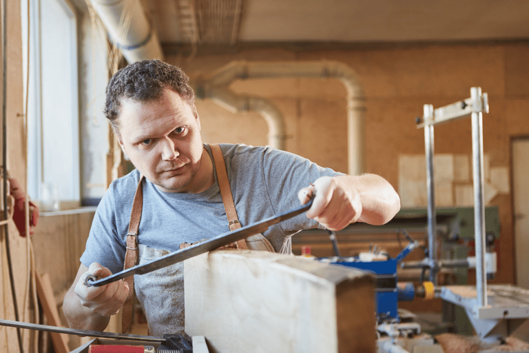 a man in a workshop with a drawknife