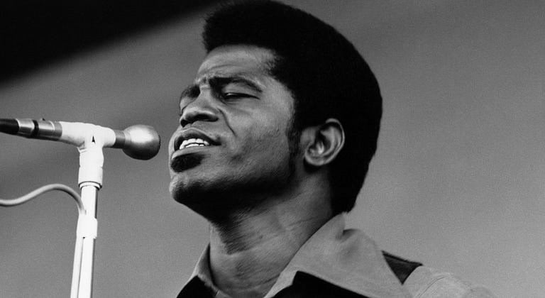 Black and White Portrait of James Brown on Stage singing into a microphone