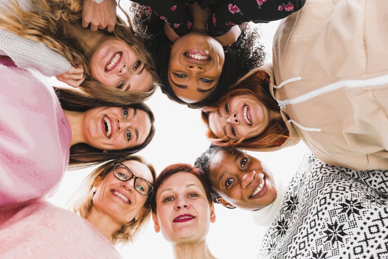 Une cercle de femmes souriantes qui regardent l'objectif en plongée. 