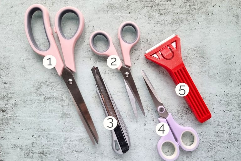 A set of five card making tools: 3 pairs of scissors, craft knife and glass scraper