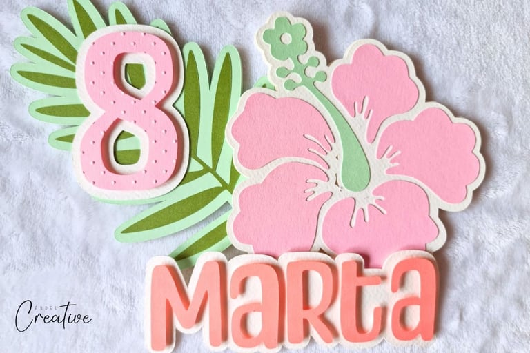 Big pink tropical  flower and leaf with number 8 on it. Name Marta sitting next to them. All made wi