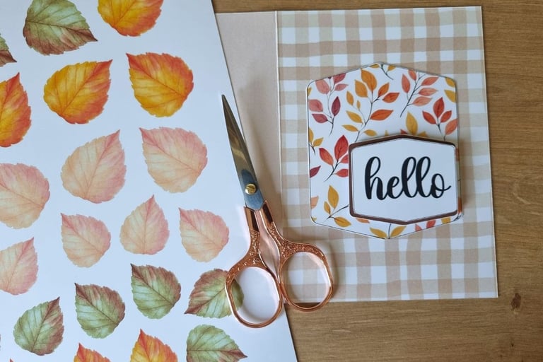 A crafting setup on a wooden table with scissors and fall card