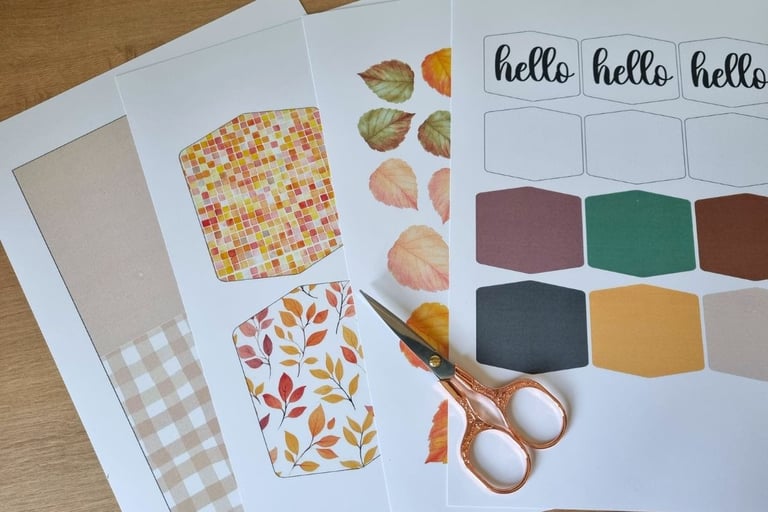 Crafting materials on a wooden table include colorful papers with autumn leaves and fall colors