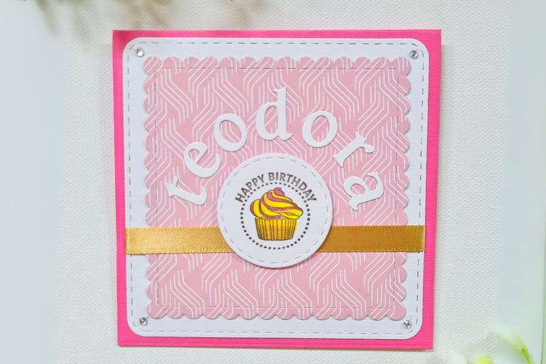 Pink birthday card with white border features "Happy Birthday" text and name "Teodora" and a cupcake