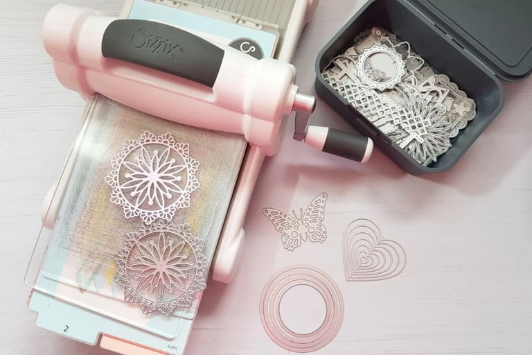 Sizzix die cutting machine with die cuts on a white table