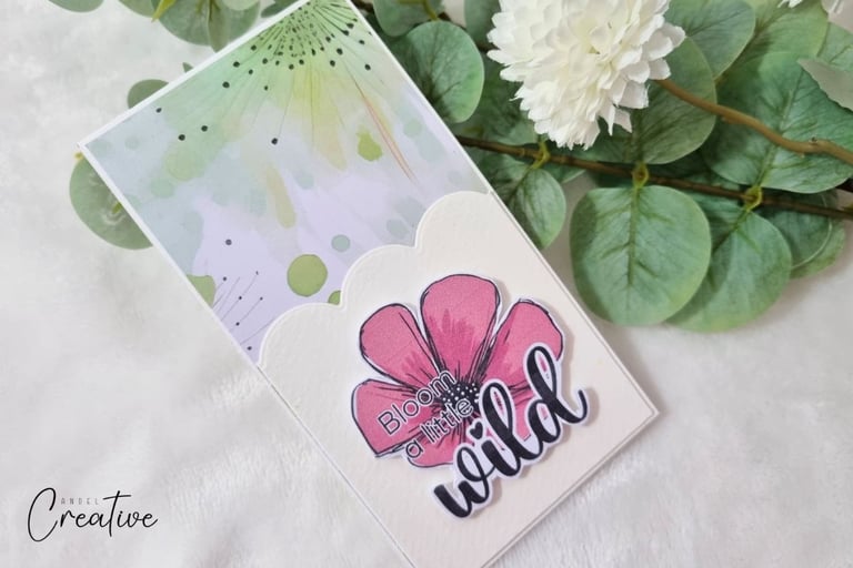 Greeting card with pastel watercolor background and "Bloom a little wild" sentiment