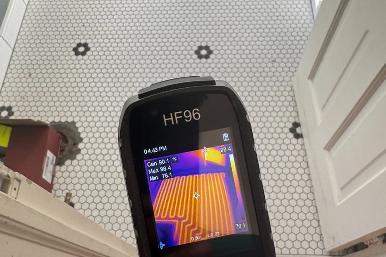 Thermal imaging camera displaying heated floor coils beneath a white and black hexagonal tile bathroom floor.