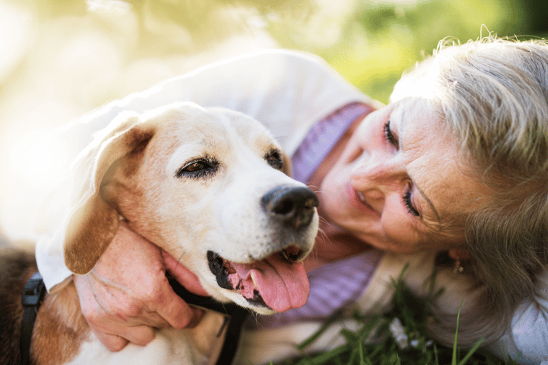a woman is laying on the grass embracing her dog