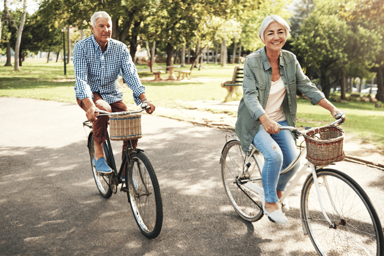 an older man and woman riding bicycles in a park