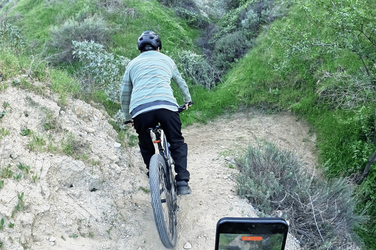 Mountain biker approaching a tight trail switchback at controlled speed before performing a stoppie