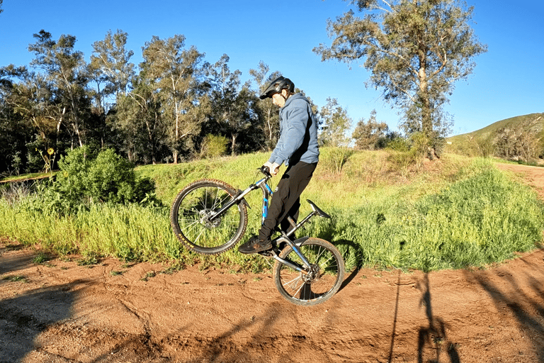 Mountain biker lifting the front wheel and bringing bars close to hips on a J hop