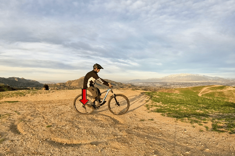 Rider shifting body weight back over rear tire to do a rear wheel lift