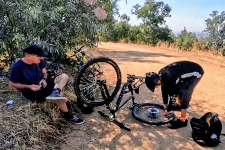2 mountain bikers with a bike upside down fixing a flat tire