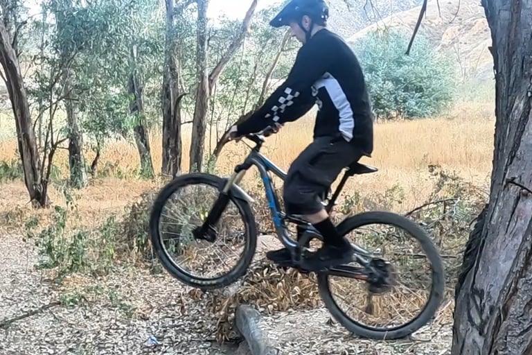 mountain bike rider lifting front wheel using downward pedal stroke during wheelie drop