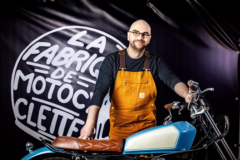 Homme barbu à lunettes en salopette jaune posant avec sa moto