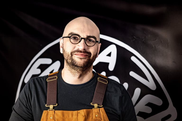 Homme avec une barbe et des lunettes posant devant une banderolle noire