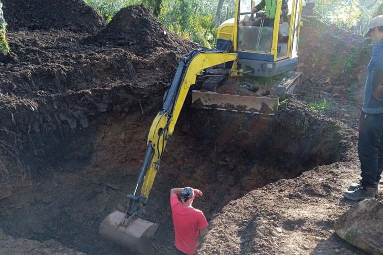 Excavator digging natural pool under expert supervision during Aqua Vitae construction phase