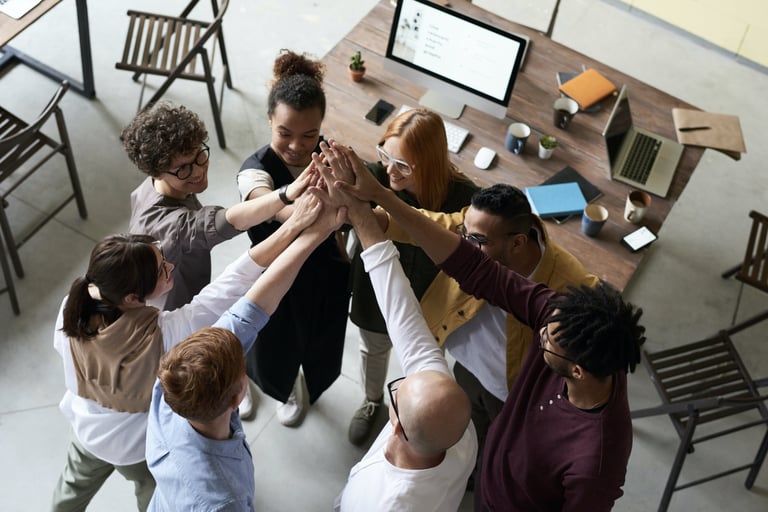 A group of people in an office, hands raised, ready to assist.