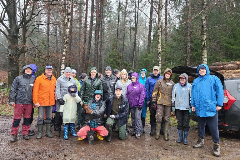 Jörg Grube mit einer Allwetterjacke in der Hocke vor einer Gruppe Männer