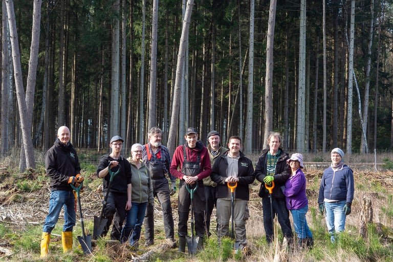 Jörg Grube mit Gummistiefeln im Wald mit einer Gruppe von Menschen