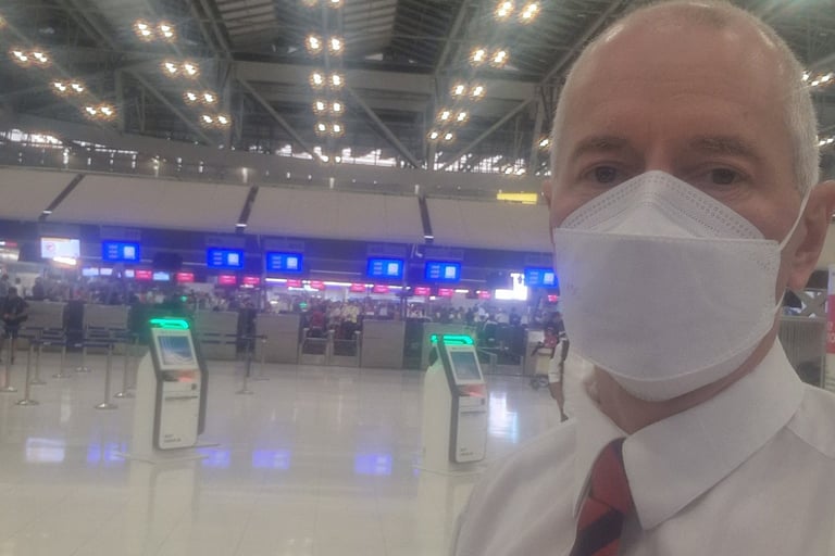 Jörg Grube mit Maske, weißem Hemd und Krawatte im leeren Flughafengebäude