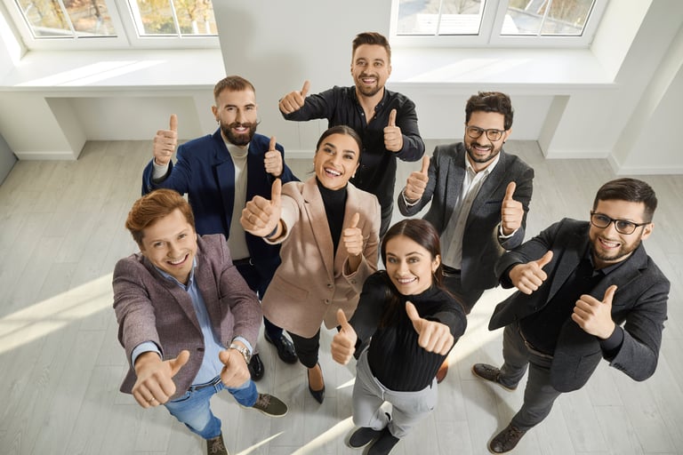 Grupa osób patrząca w górę z kciukami do góry