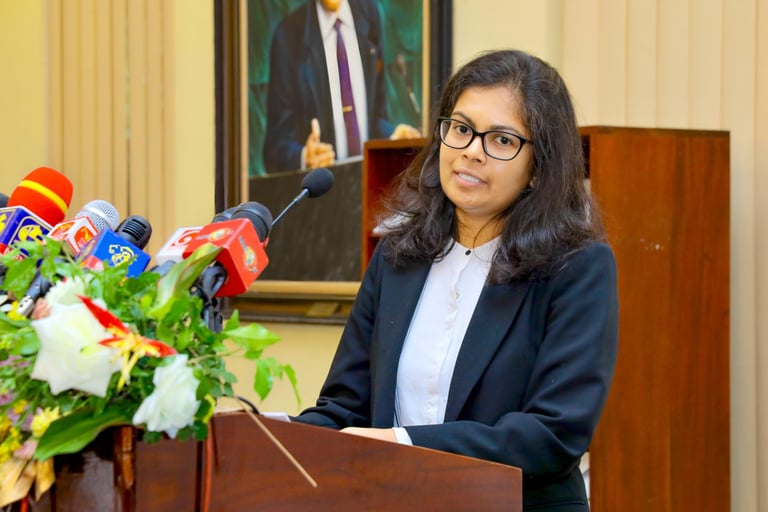 a woman in a suit and glasses speaking into a microphone