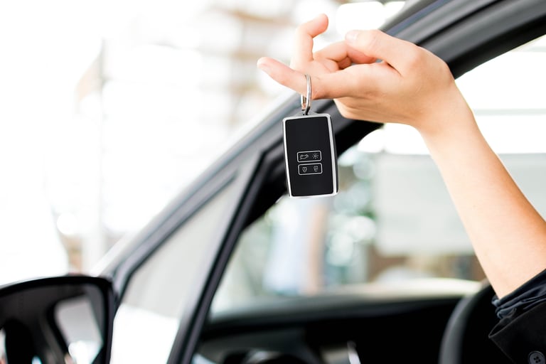 Vrouw die hand uit auto steekt met in haar hand een sleutelhoesje.