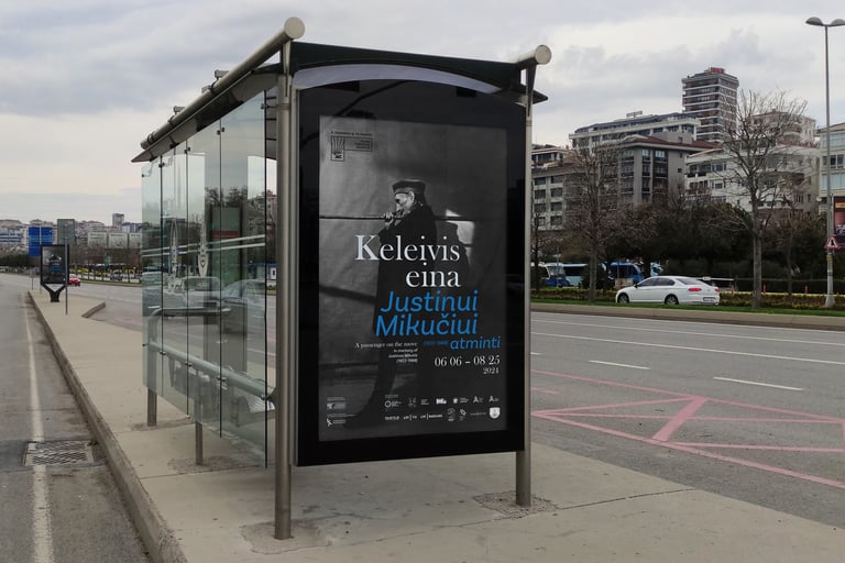 Plakatas mieste, autobusų stotelėje. Plakato dizianas išlaikytas toks pats kaip pagrindinio plakato.