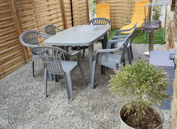 Terrasse ensoleillée avec salon de jardin et parasol. Parfaite pour les repas en plein air. Location de vacances