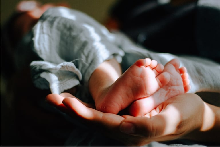 Eine Person hält Baby_Füße in der Hand