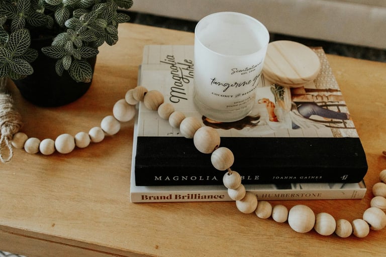 wooden table with a potted plant, a pile of books, a candle and a wooden bead garland