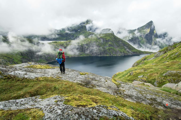 person hiking in the moutains looking down at a lake