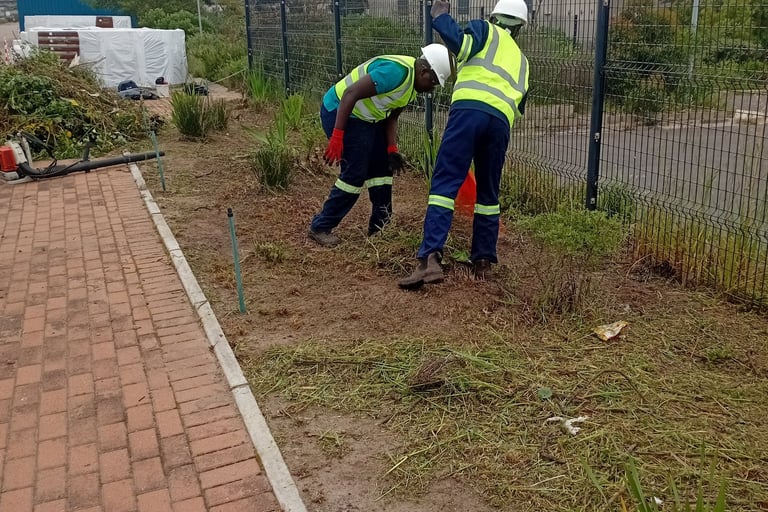 two men in safety vests working on a brick wall