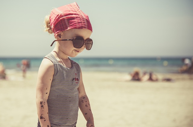 petite fille à la plage avec protection solaire et lunette