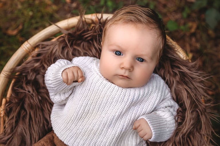 a baby in a basket with a white sweater