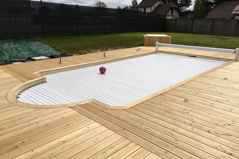 Piscine extérieure entourée d'une terrasse en bois conçue par la menuiserie Glohr