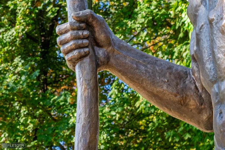 Close-up of Saint Christopher’s hand gripping a wooden staff, symbolizing pilgrimage and sanctuary.