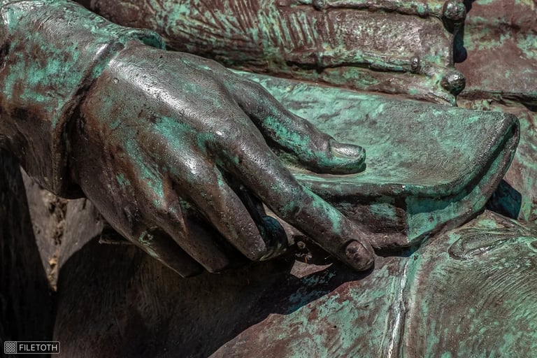 Close-up of Kölcsey's hand resting on a book in his lap.