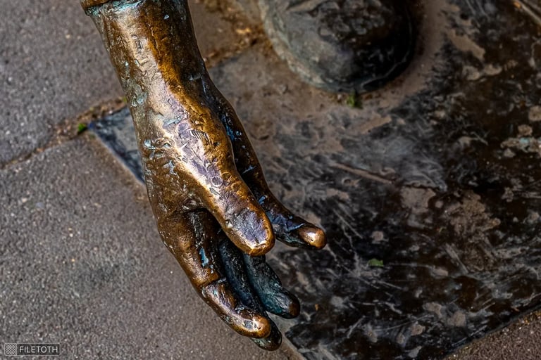Close-up of Ernő Nemecsek’s hands throwing a marble.