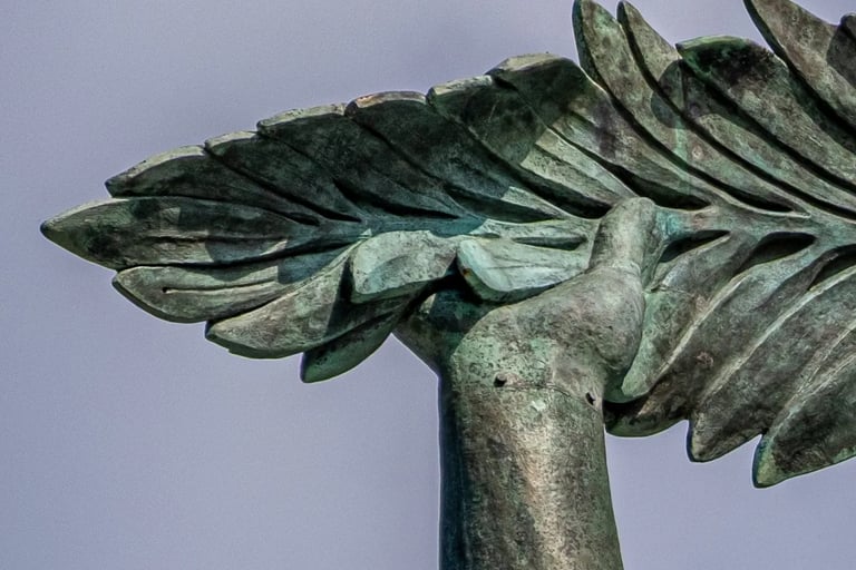 Liberty Statue’s hand holding the palm leaf high against the sky.