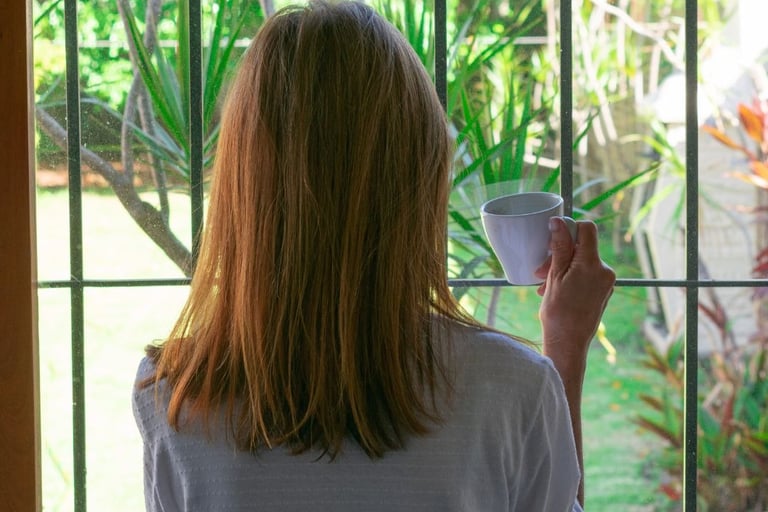 a woman holding a cup of coffee in front of a window