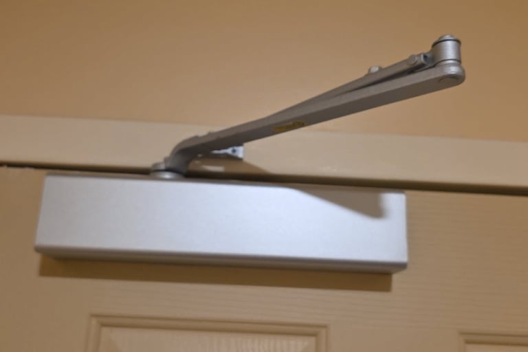 Commercial door closer installed above interior door for code compliance