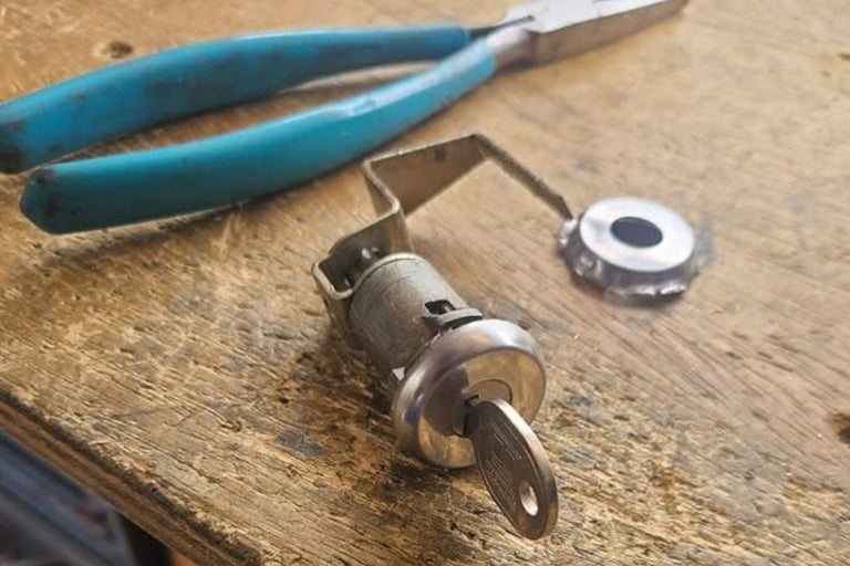 Car ignition cylinder repair by Jack’s Locksmith in Marion NC with key inserted and tools on workbench.