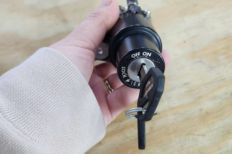 Hand holding a motorcycle ignition cylinder with key inserted