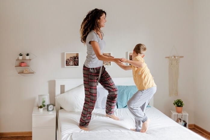 Une famille saute joyeusement sur un lit, complices après une nuit sans accident.