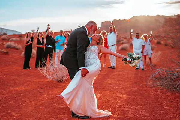 a bride and groom kissing in the desert
