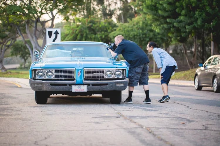A cameraman and a director filming a classic car