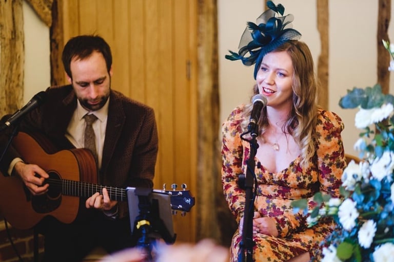 Beautiful stylish wedding singer with man playing acoustic guitar
