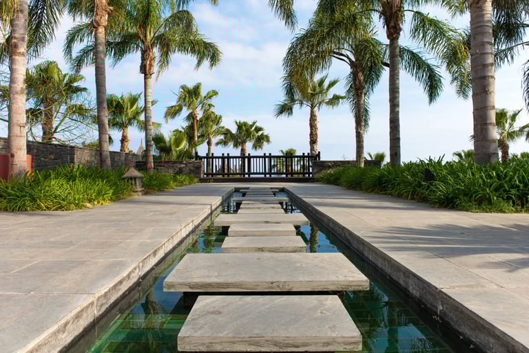 a stone path leading to a pool with stepping stones